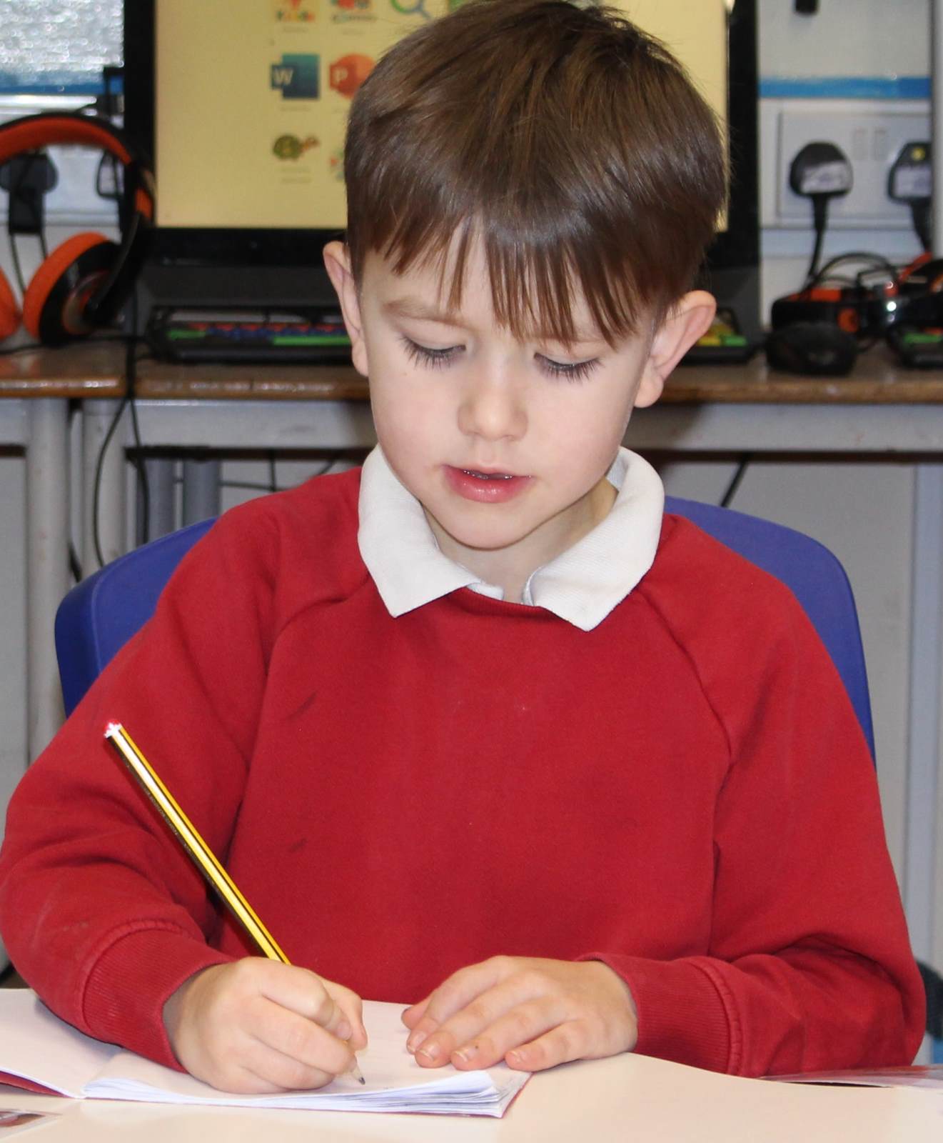 Phonics writing Boy with a pencil writing in phonics book.