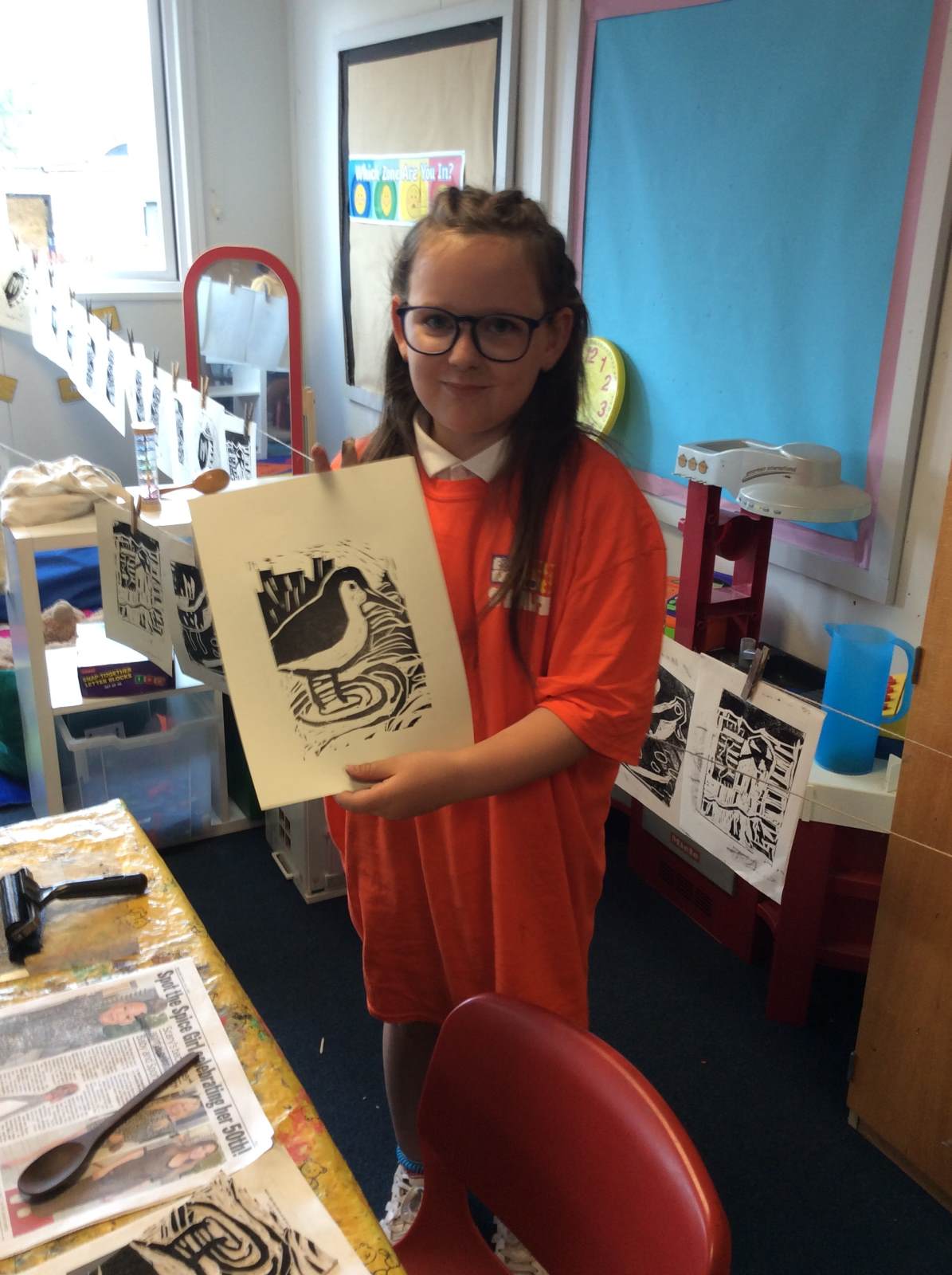 A girl holding a lino print of a water bird